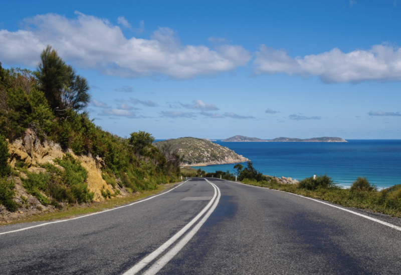 Curving coastal road near cliff with sea in background
